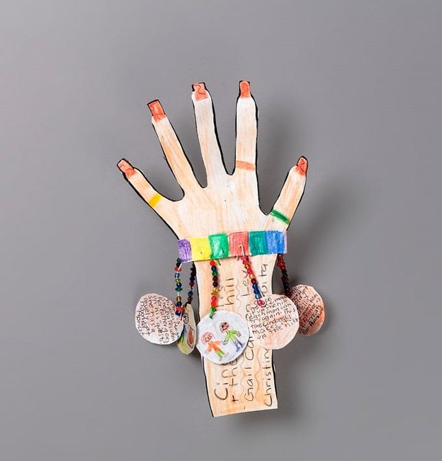 A decorated paper hand with color charms hanging off of it